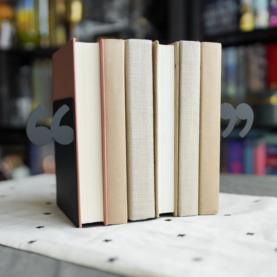 The Quotation Mark Bookends are black matte metal bookends with a quote on each end.