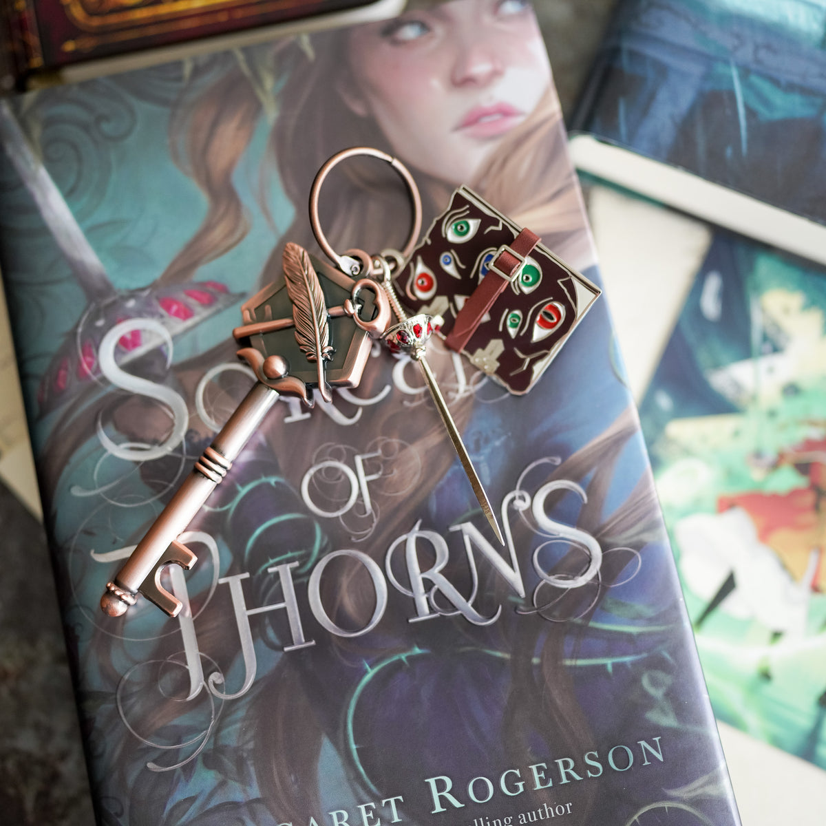 Sorcery of Thorns Key is bronze metal and has a sword charm and a mini grimoire with eyes looking at you