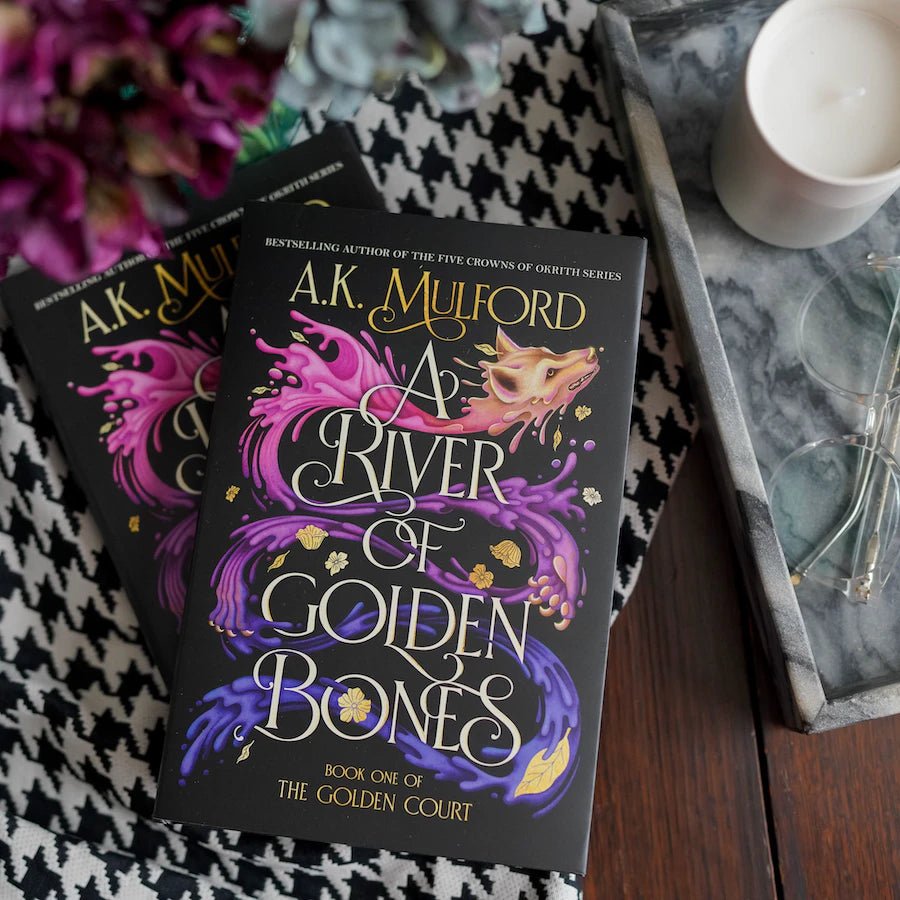 A River of Golden Bones by A.K. Mulford hardback book with black cover and a multicolored wolf that appears like it's made from paint splotches.