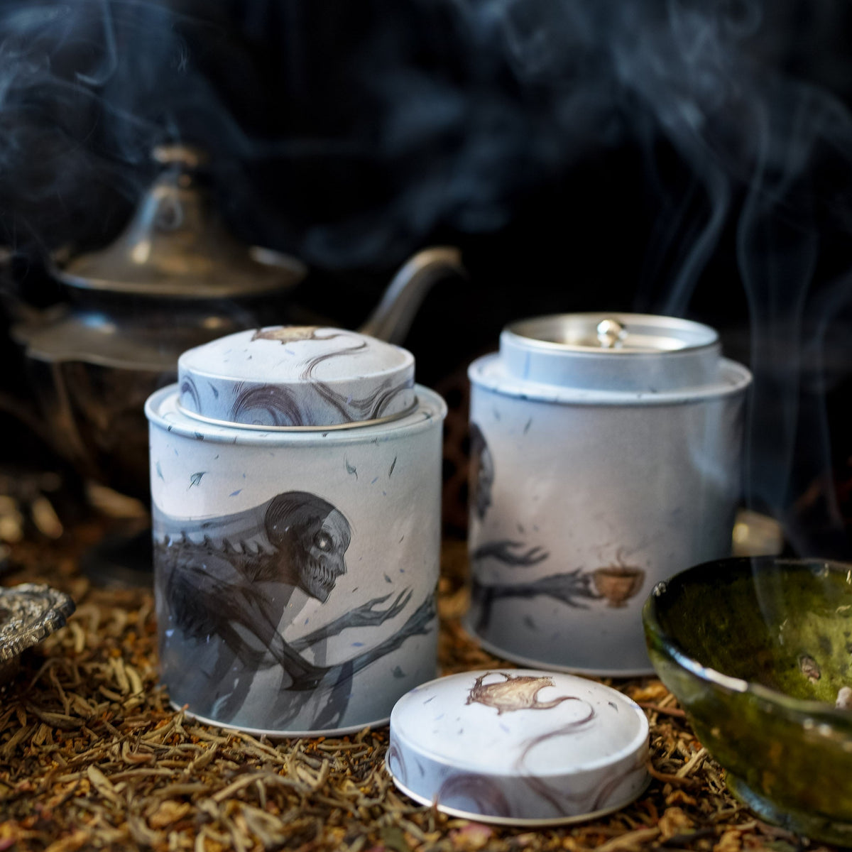 Suriel Tea Company Tin in blue and gray with a black Suriel from ACOTAR spilling the tea from a golden teacup.