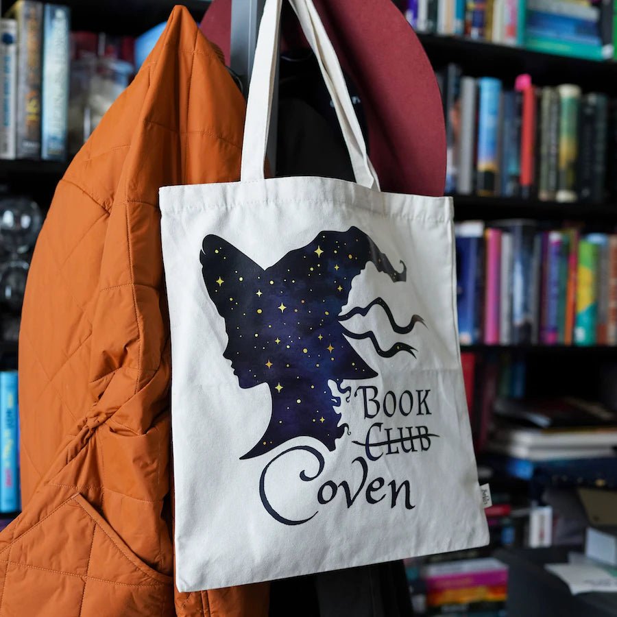 A canvas book tote with a witch silhouette adorned with gold stars. The tote reads Book Club Coven; &quot;club&quot; is crossed out.