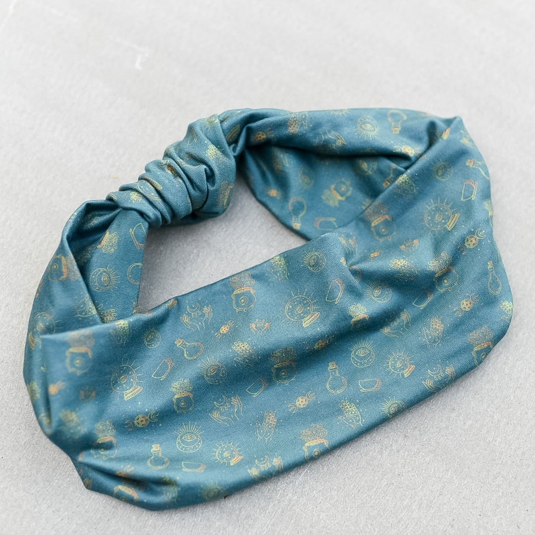 close-up of blue headband with light cream colored witchy motifs