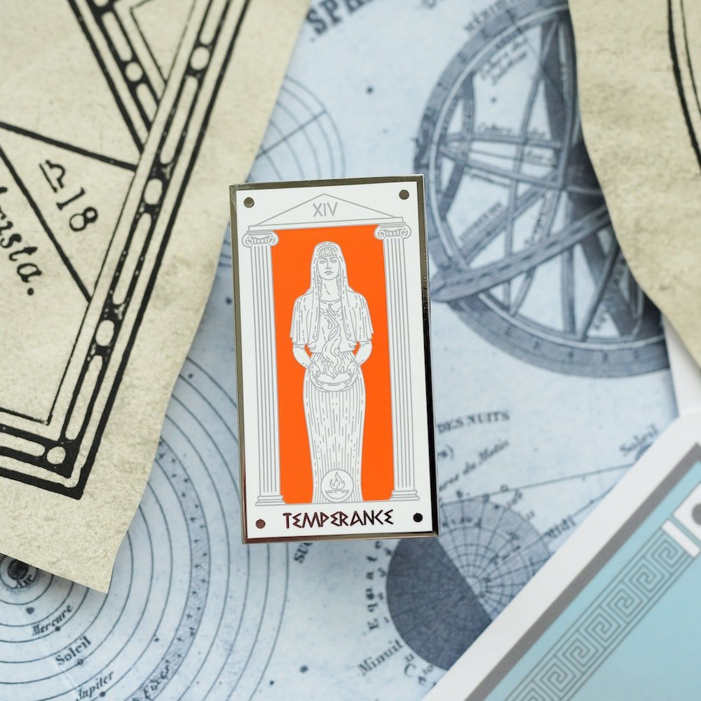 On the Hestia Temperance, Mythology Tarot Enamel Pin, Hestia holds a cup of fire in front of an orange background.