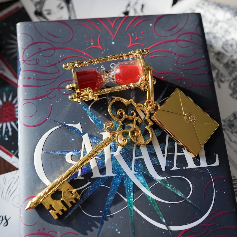 A key including two charms: an hourglass game piece with red sand, and an envelope with the engraved ticket inside