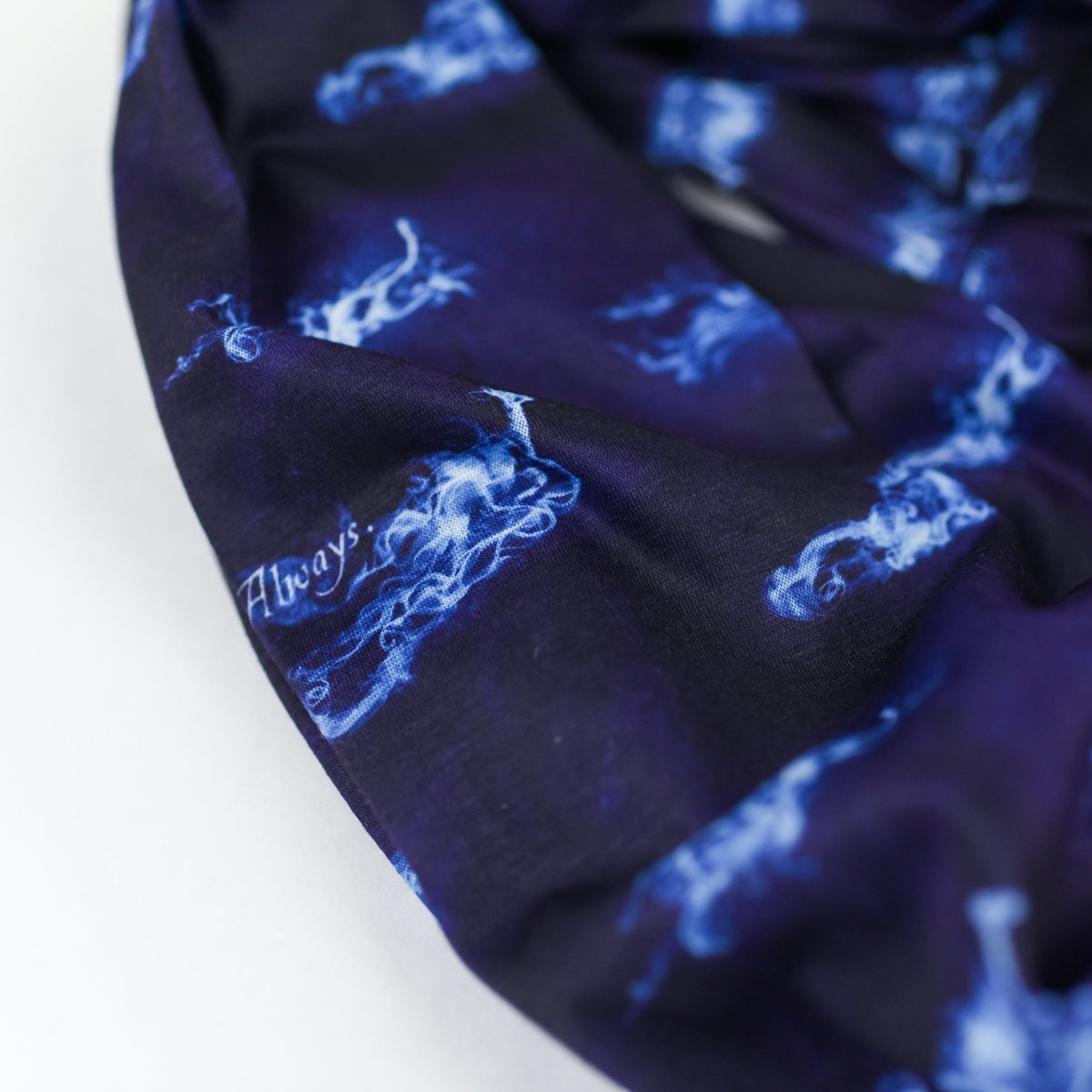 Close up of the fabric of a Navy blue and black Magical Animal Familiar Scarf with white wispy creatures