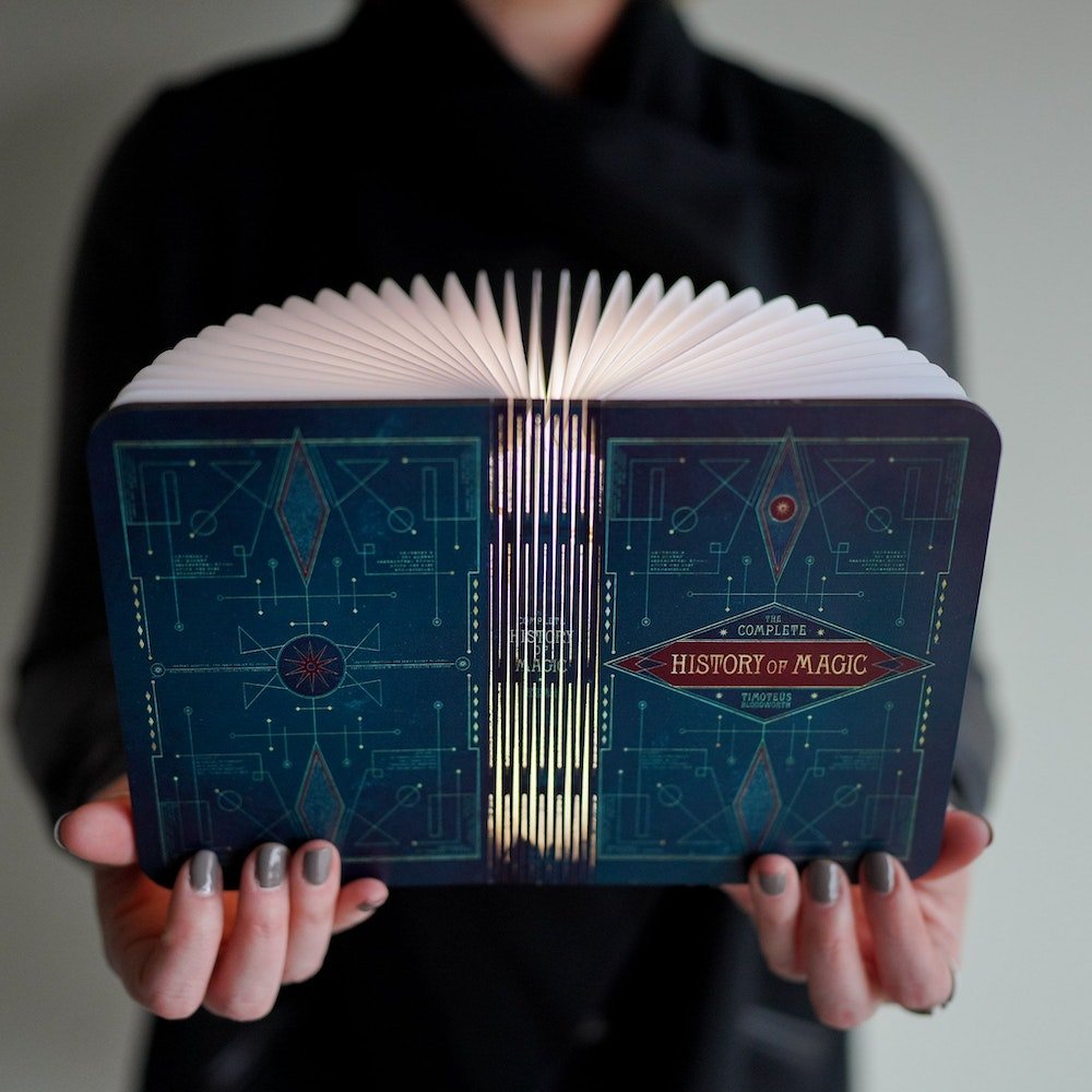 The Complete History Of Magic Book Lamp resembling a hardcover wizard textbook with magical designs