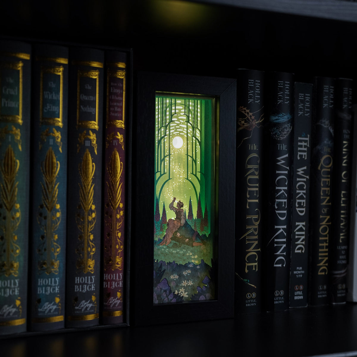 The Cruel Prince Elfhame Bookshelf Alley with an image of Jude and Cardan sitting together in a forest.