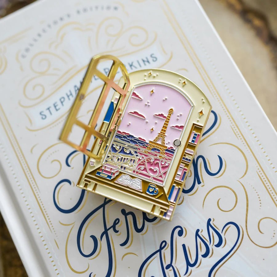 Anna and the French Kiss Literary Window Enamel Pin shows a writing desk and a French window that hinges open to reveal Paris