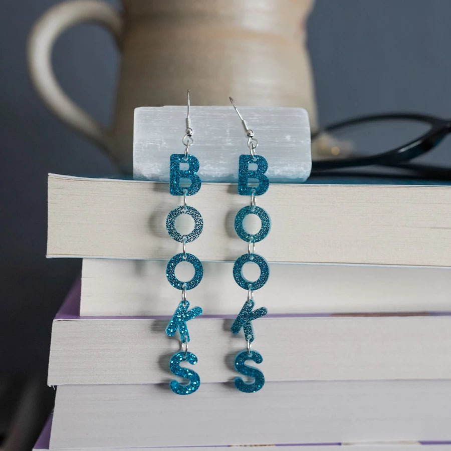 LitJoy's Books Acrylic Earrings are shimmering blue earrings that spell out the word BOOKS in dangly letters on each one.