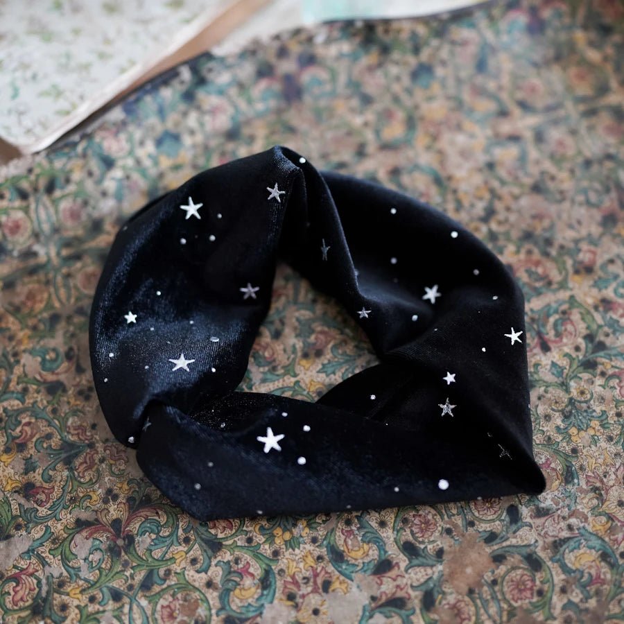  Celestial Velvet Headband is a black velvet knotted headband with stars, moons, and orbs in a shimmery silver print.