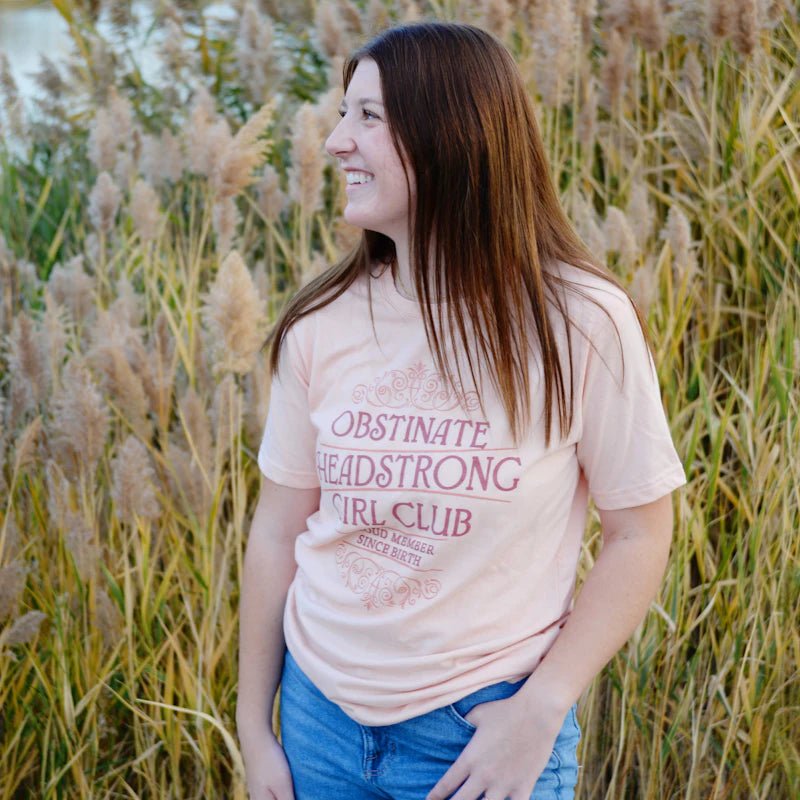 Dust blush colored crew neck Pride and Prejudice shirt with "Obstinate Headstrong Girl Club— Proud member since birth“ design