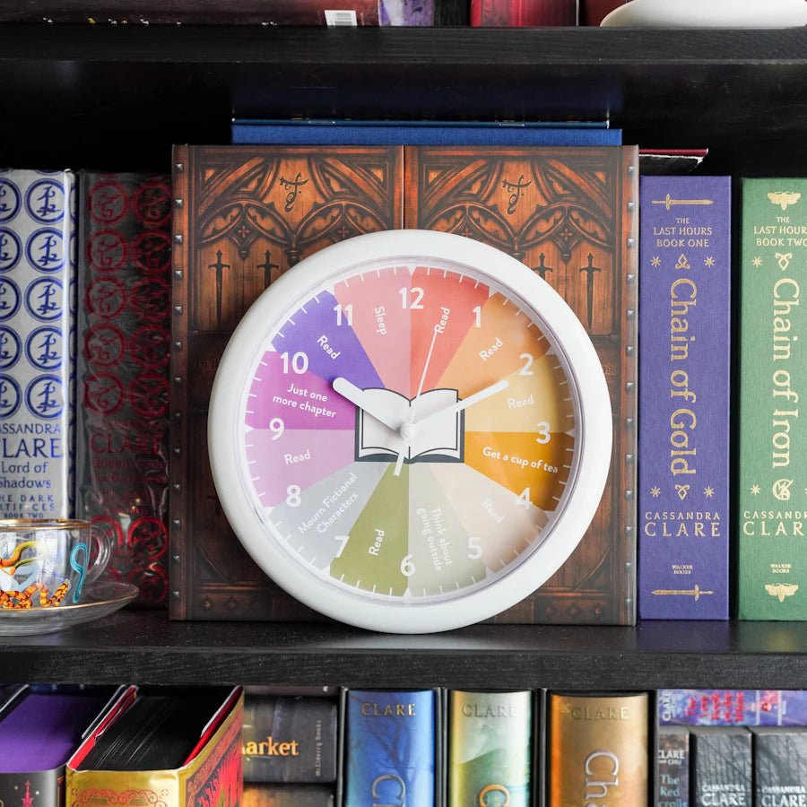 Colorful plastic analog clock with different reader activities at each hour - battery-operated and built for wall-hanging 