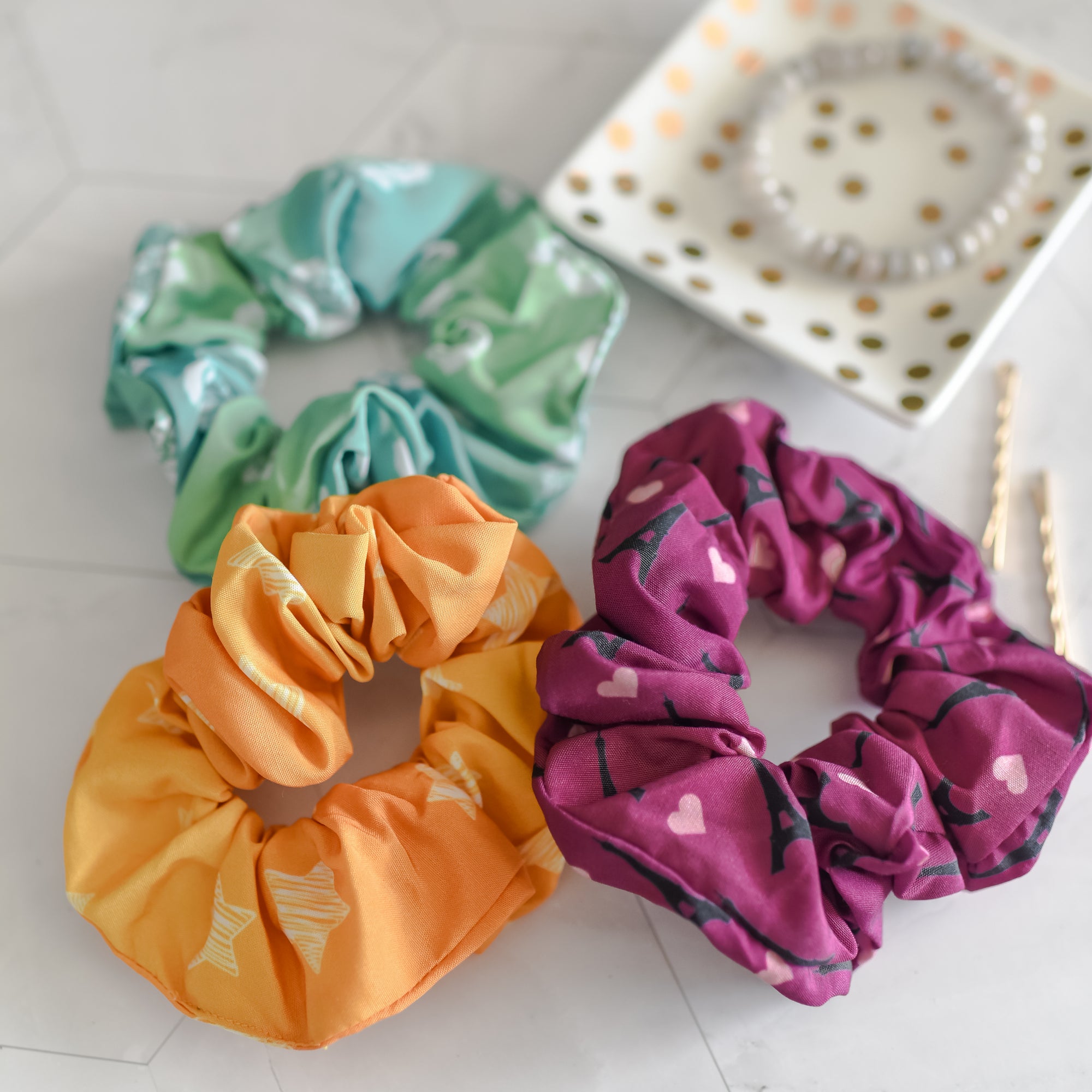 3 Anna and the French Kiss scrunchies: light green with roses, purple with hearts and Eiffel Towers, and yellow with stars