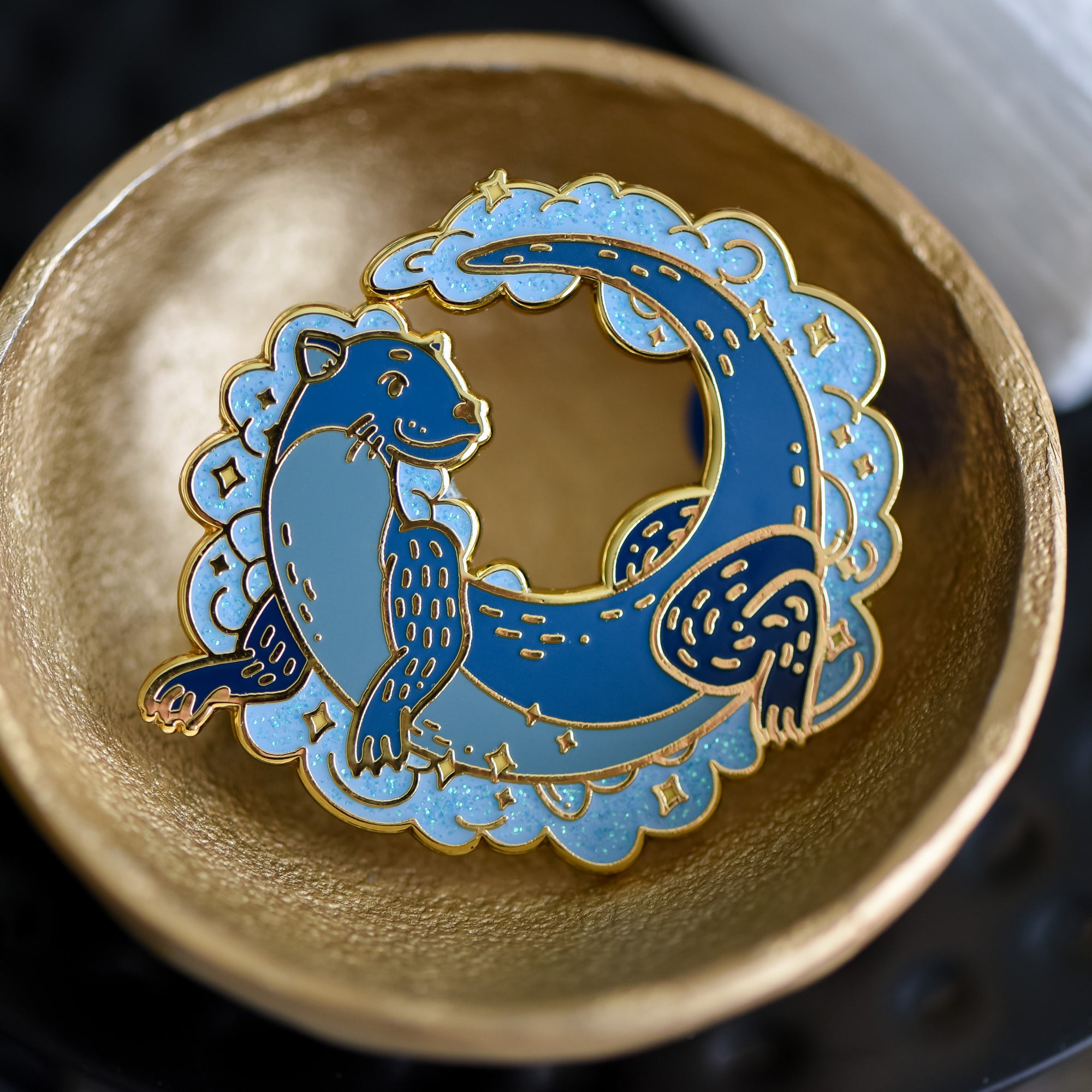 Otter Magical Animal Familiar Cirtter Collection Enamel Pin is a blue otter with a glittery cloud around him.