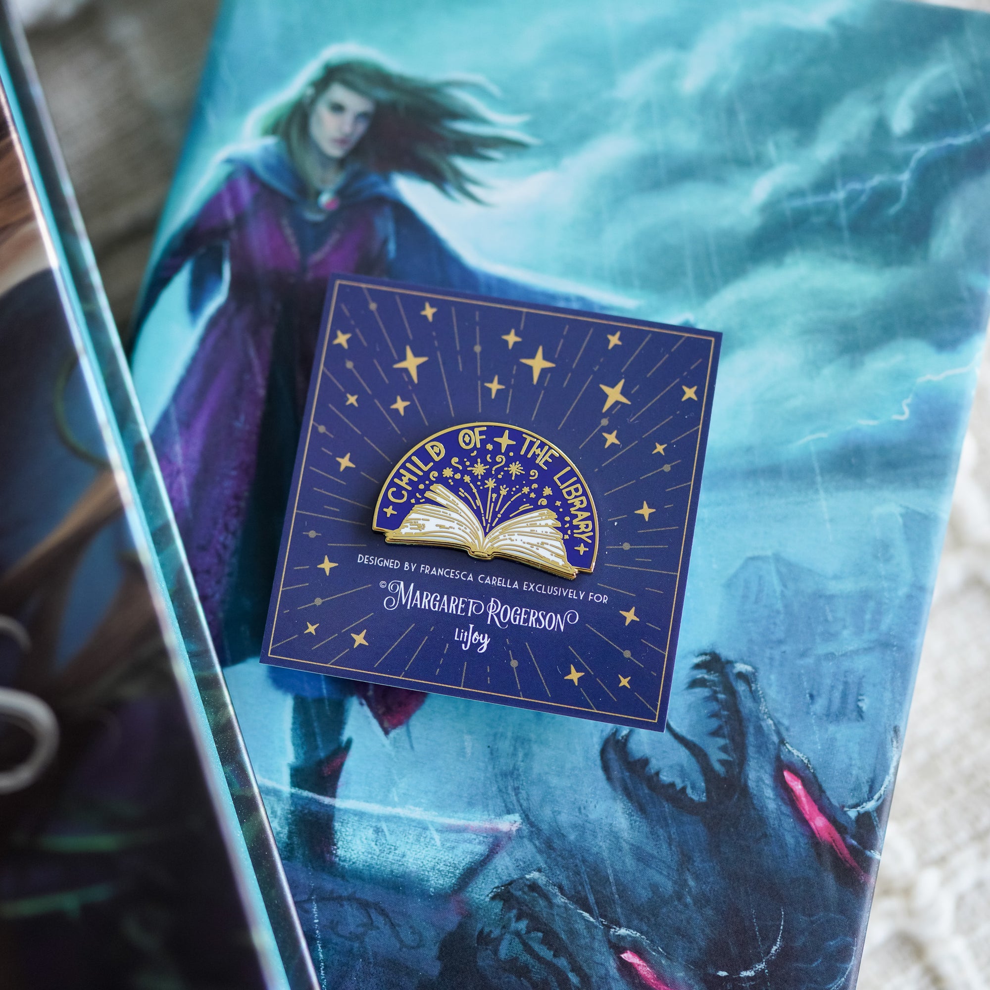 Child of the Library Enamel Pin includes an open book with the pin's name on it and golden stars on the purple background