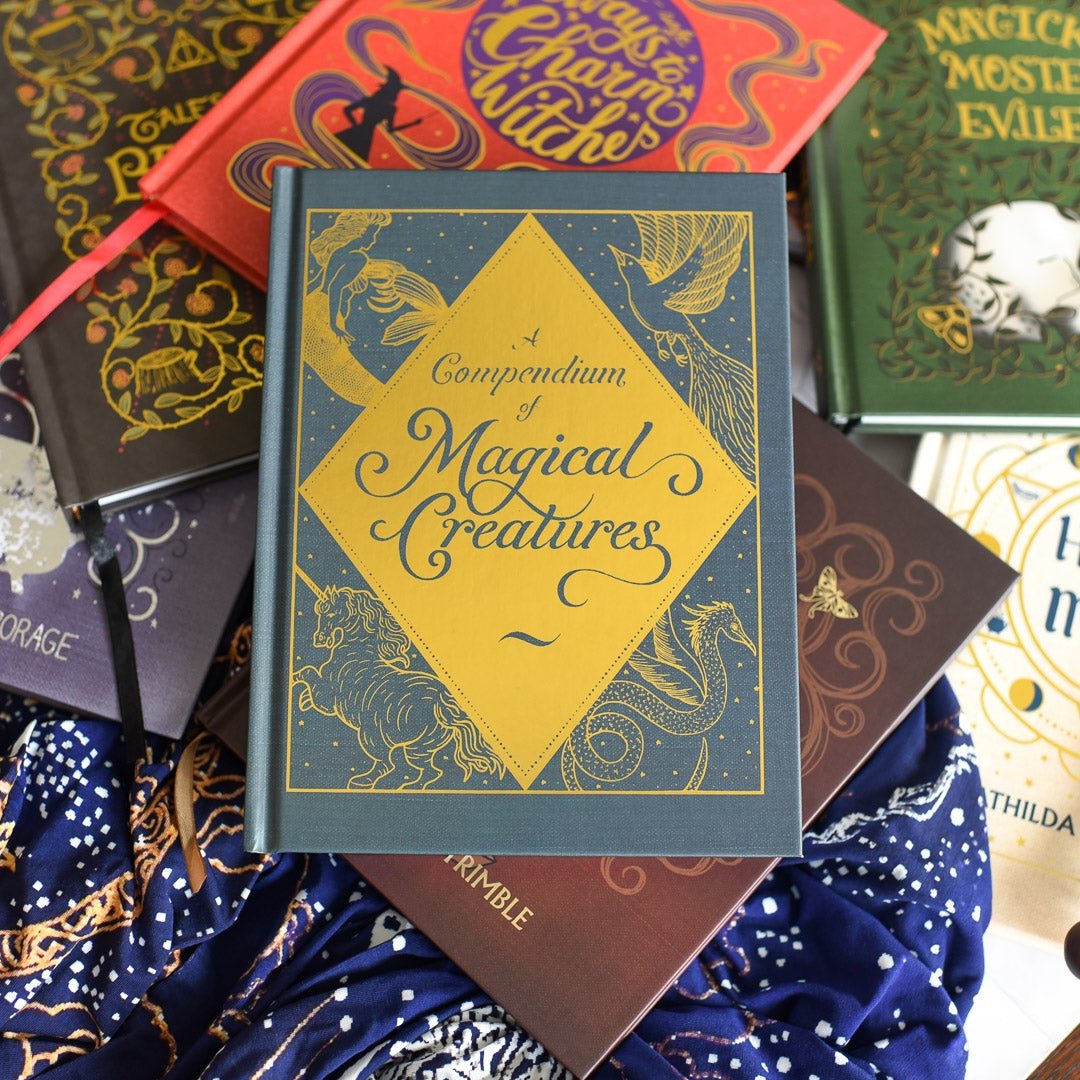 A Compendium of Magical Creatures Notebook with a blue cover and metallic foil featuring images of magical creatures printed on the front.