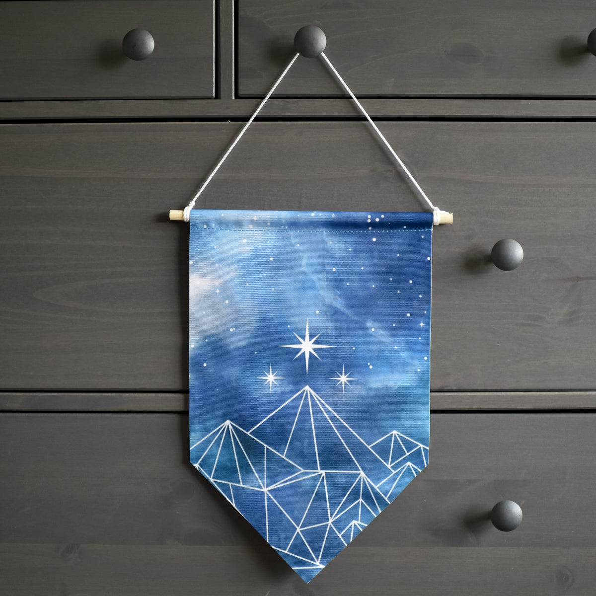 ACOTAR Velaris Pin Banner hanging with wood dowel &amp; rope. Blue night sky fabric with mountains of geometric white lines.