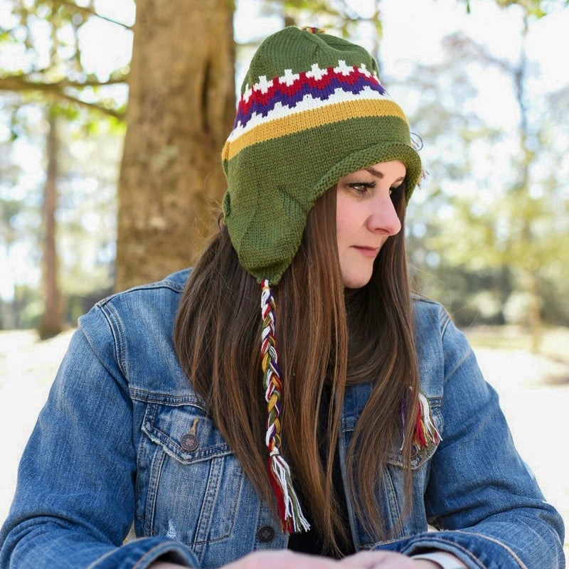 Knitted olive Animal Cracker Beanie with white, red, purple and gold design and long braided yarn on top and on earflaps