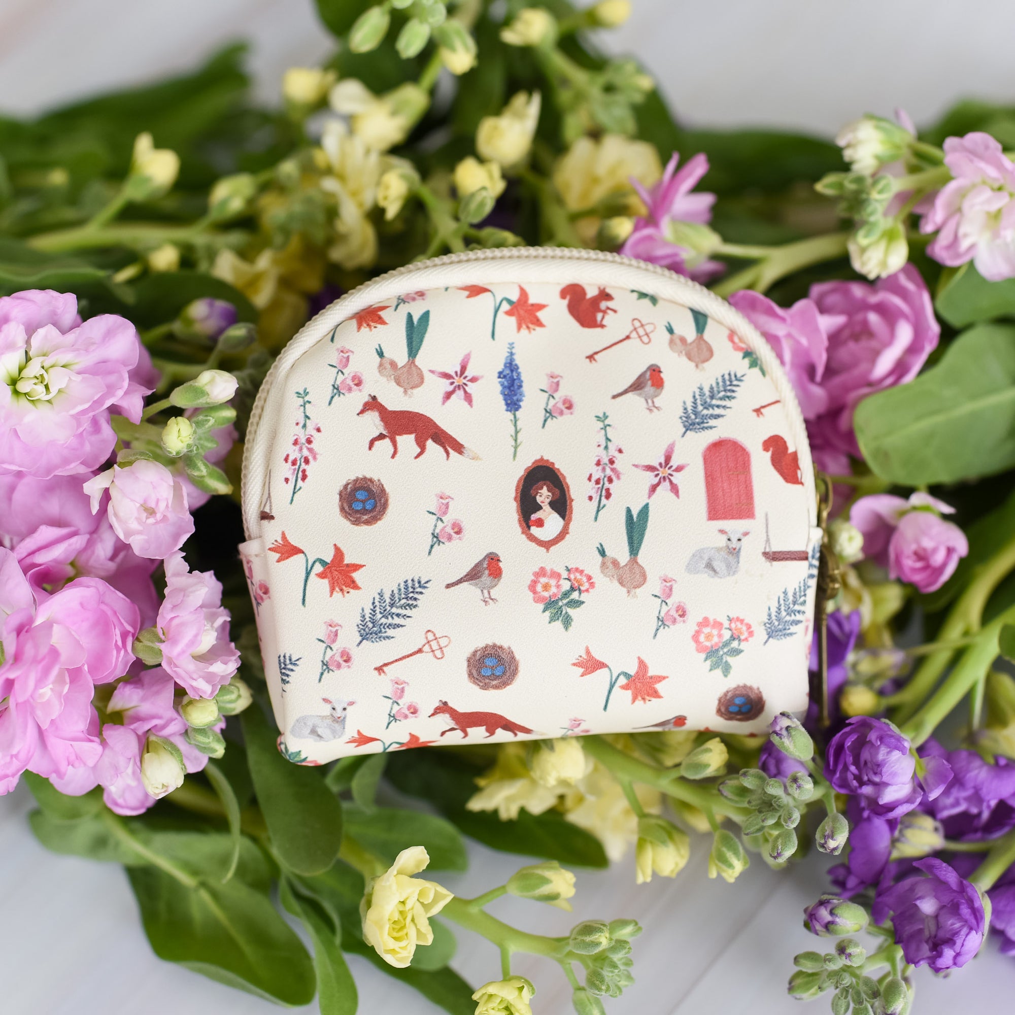 The Secret Garden Coin Pouch is white with a pattern that includes a robin, key, flowers, door, squirrel, fox, and nest.