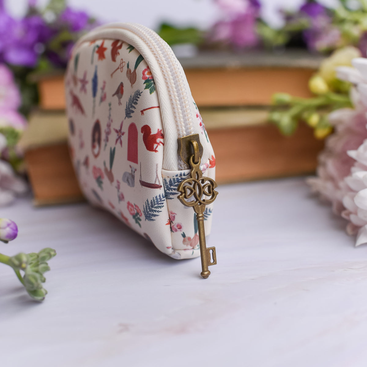 The Secret Garden Coin Pouch with key zipper pull and a pattern that includes a robin, key, flowers, door, squirrel, fox, and nest.