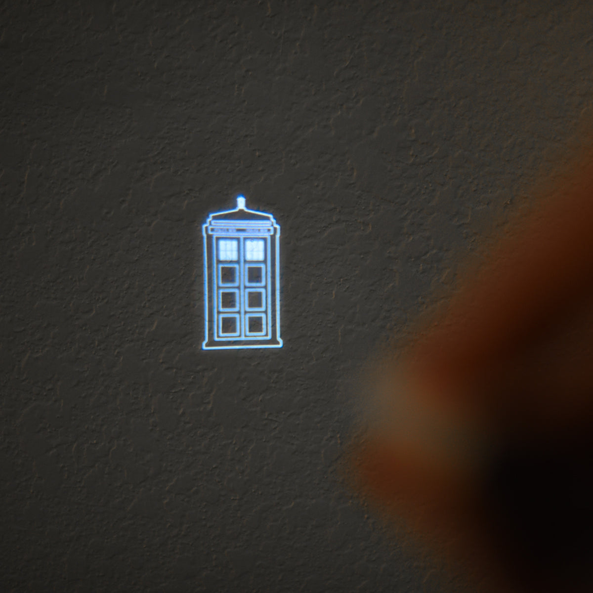 The projected symbol on a wall of the Blue TARDIS Police Box symbol 
