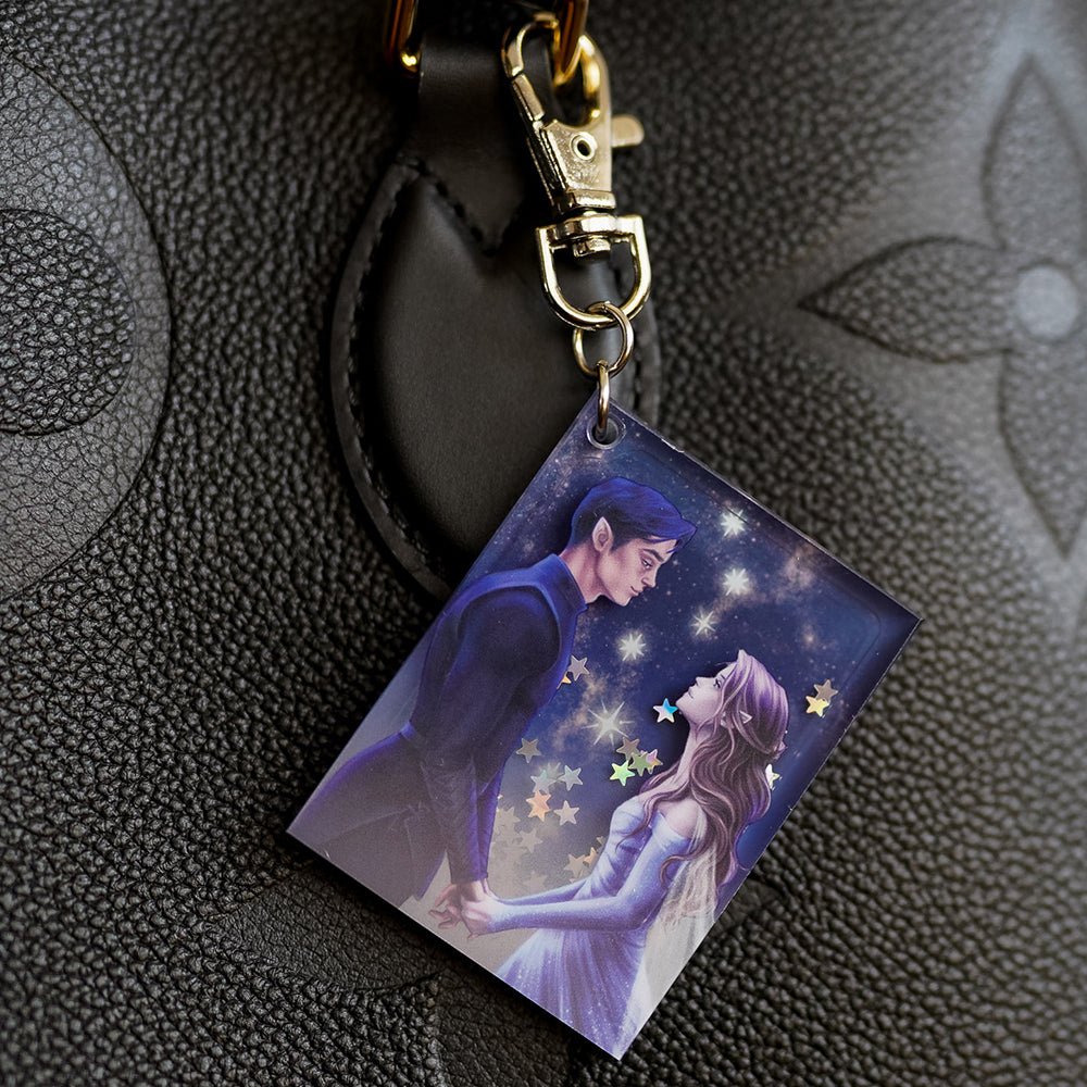 Purple and silver ACOTAR Starfall Keychain has Feyre and Rhysand holding hands with silver stars behind them.