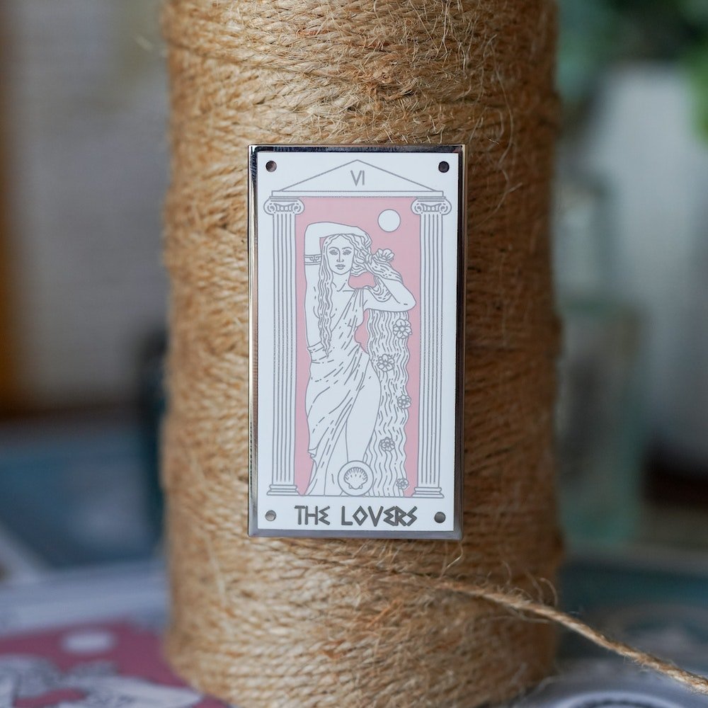 Aphrodite The Lovers, Mythology Tarot Enamel Pin with Aphrodite between two columns and the words &quot;The Lovers” below.
