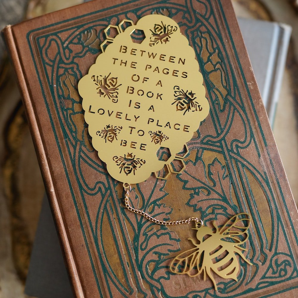 Gold “Bee”Tween the Pages Metal Bookmark with a bee charm and quote: "Between the pages of a book is a lovely place to bee.”
