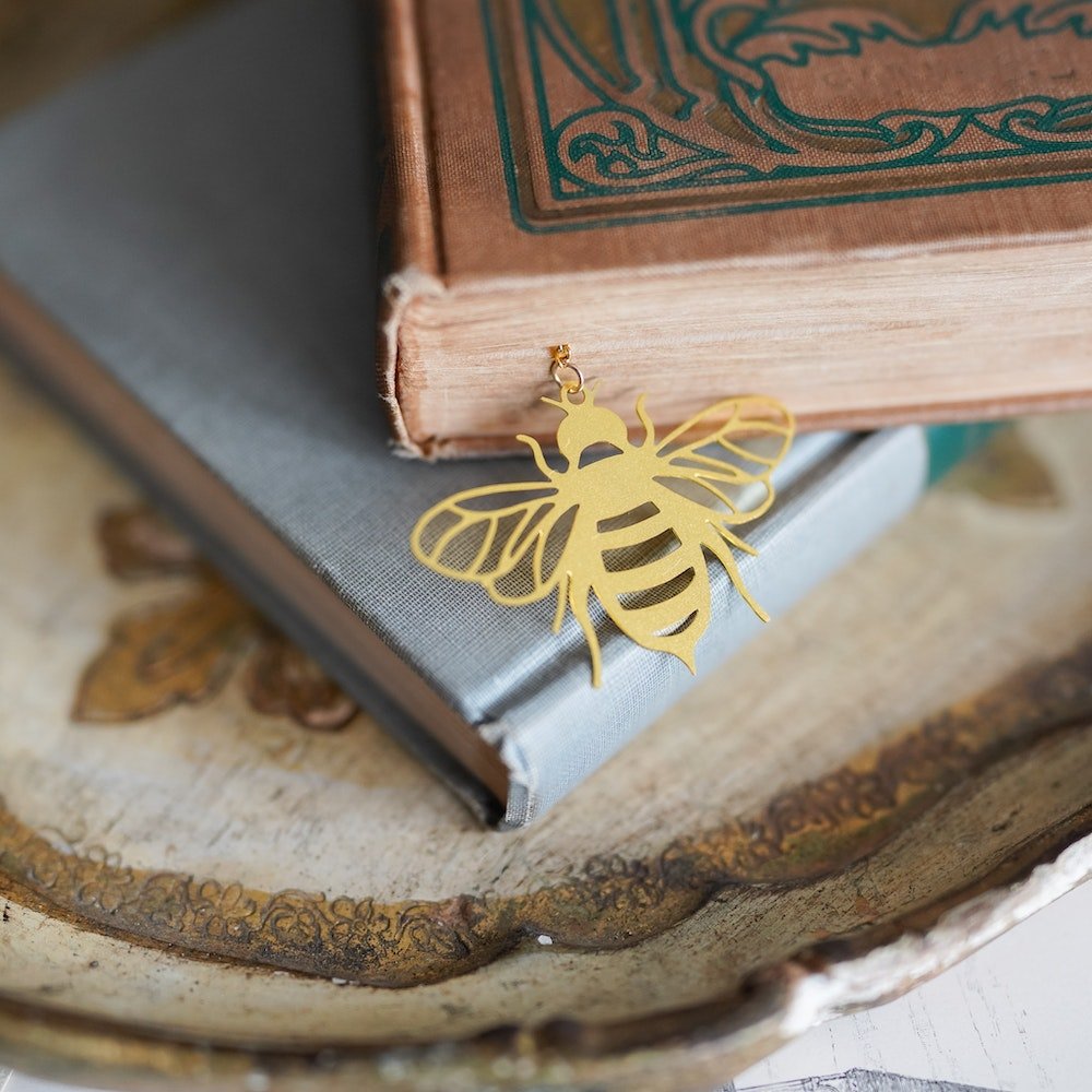 Gold “Bee”Tween the Pages Metal Bookmark with a bee charm and quote: &quot;Between the pages of a book is a lovely place to bee.”