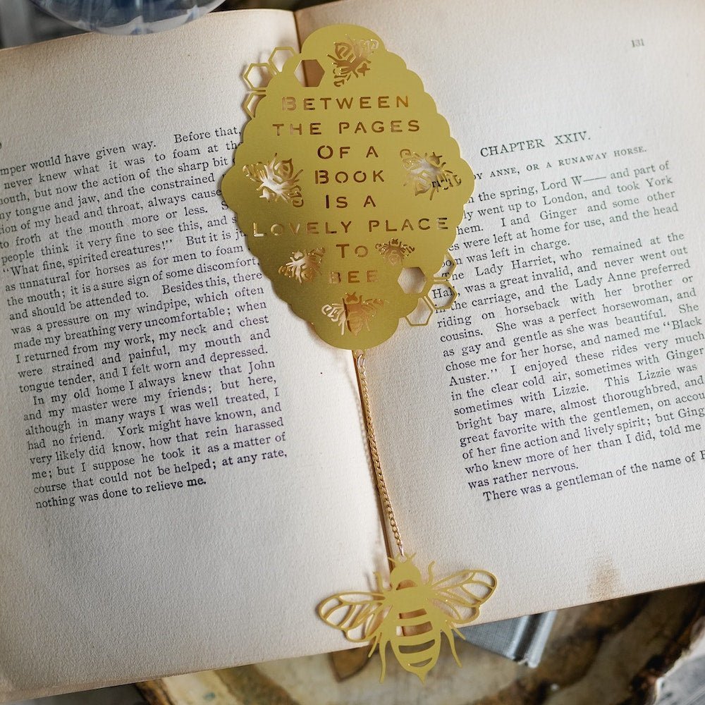 Gold “Bee”Tween the Pages Metal Bookmark with a bee charm and quote: &quot;Between the pages of a book is a lovely place to bee.”