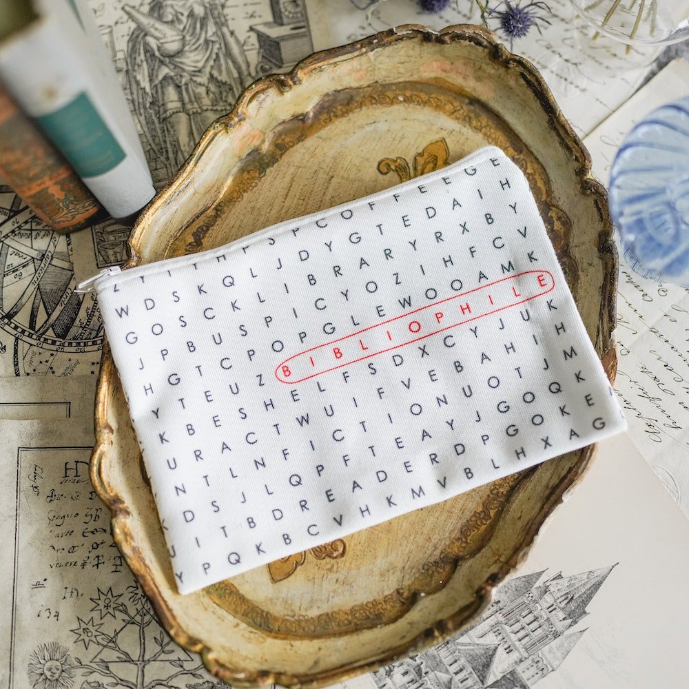 Bibliophile Word Search Zipper Pouch with a word search print and the word &quot;bibliophile&quot; circled and in red