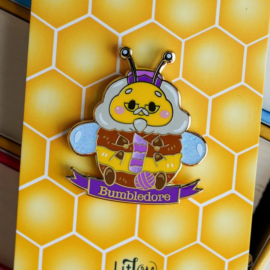 Bumbledore Bee Enamel Pin is a pin of a bee with gray hair and a beard knitting a purple sock