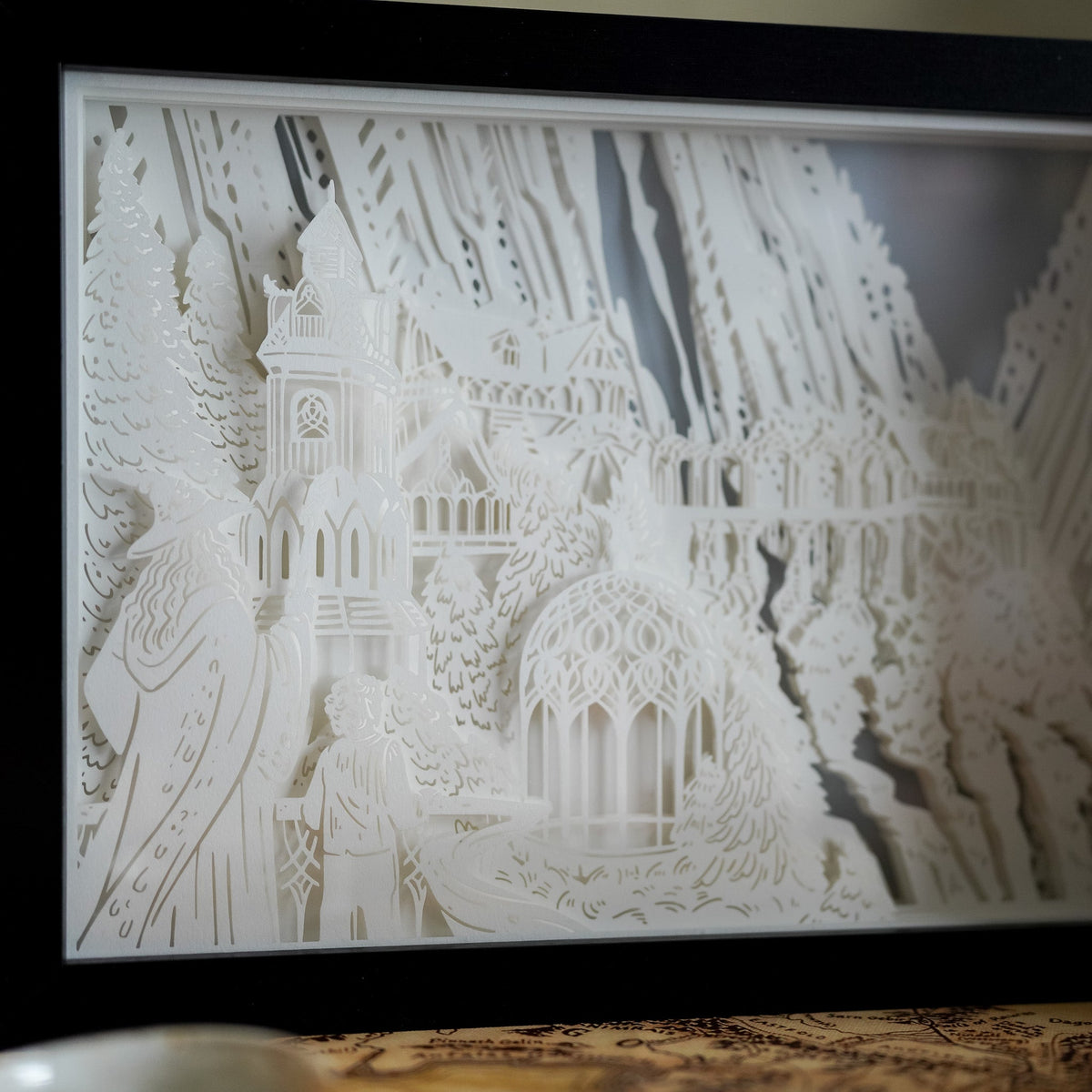 Elven Home Light Box is a blue and yellow light of a paper cut shadow box of a castle-like home in a valley