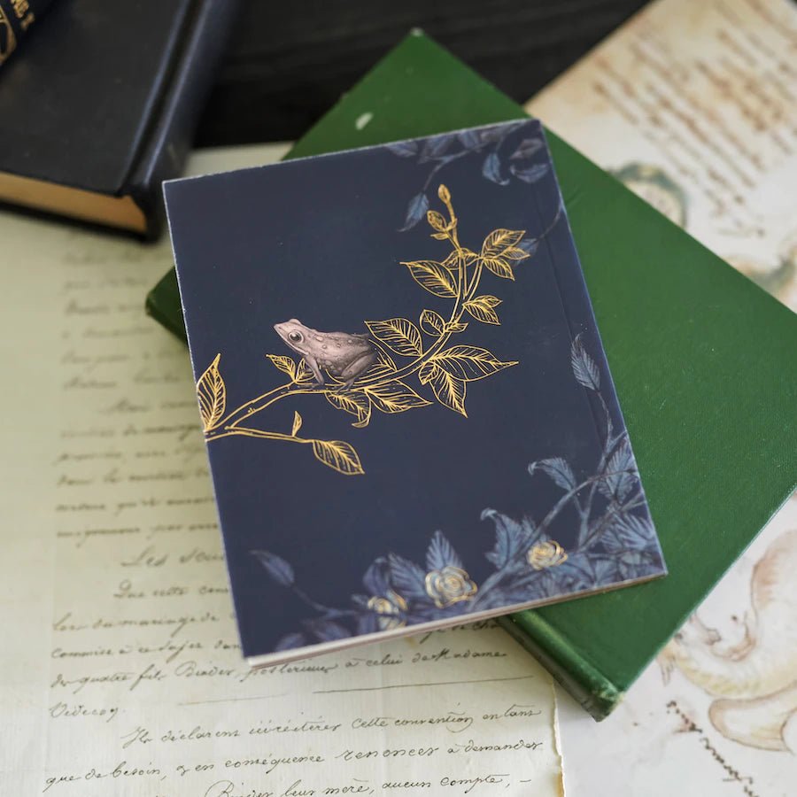 The Grimm&#39;s Fairytale Pocket-sized Storybook is a gray and pink paperback book with the title in gold foiling and gold gilded page edges