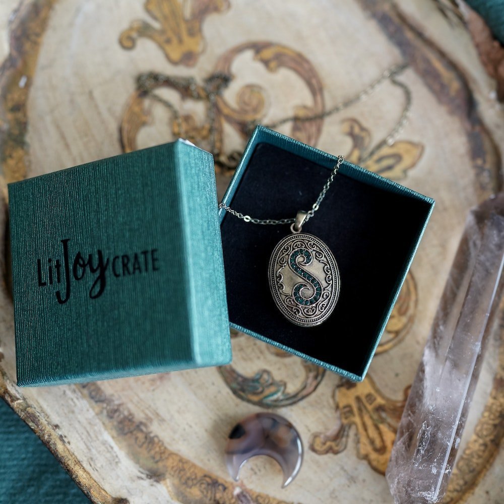 House Locket that is gem-encrusted and with the letter S on the front within a shimmery green LitJoy box