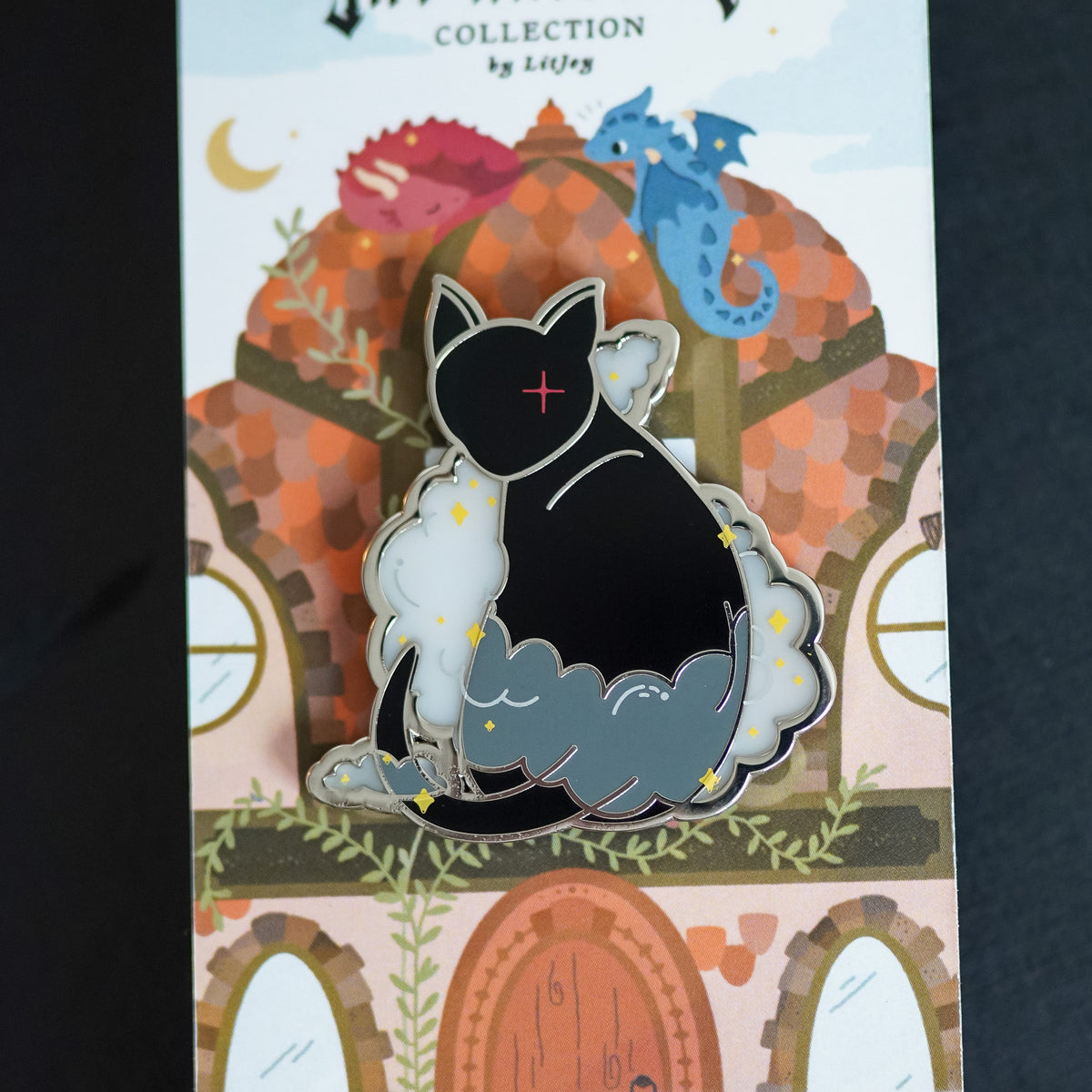 Mister Kindly Critter Collection Enamel Pin displaying a black cat surrounded by sparkles and mist inspired by the shadow daemon in Nevernight by Jay Kristoff.