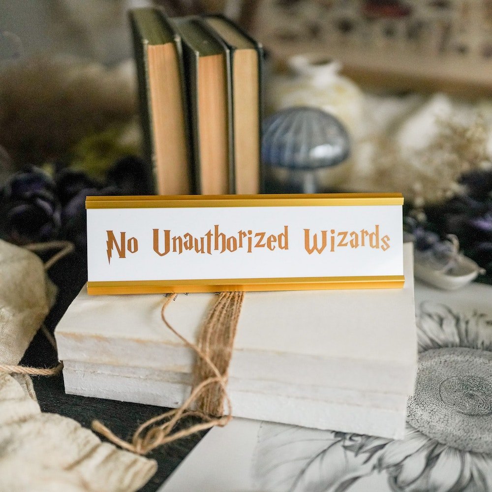 No Unauthorized Wizards Desk Name Plate with gold stand and gold letters on white background