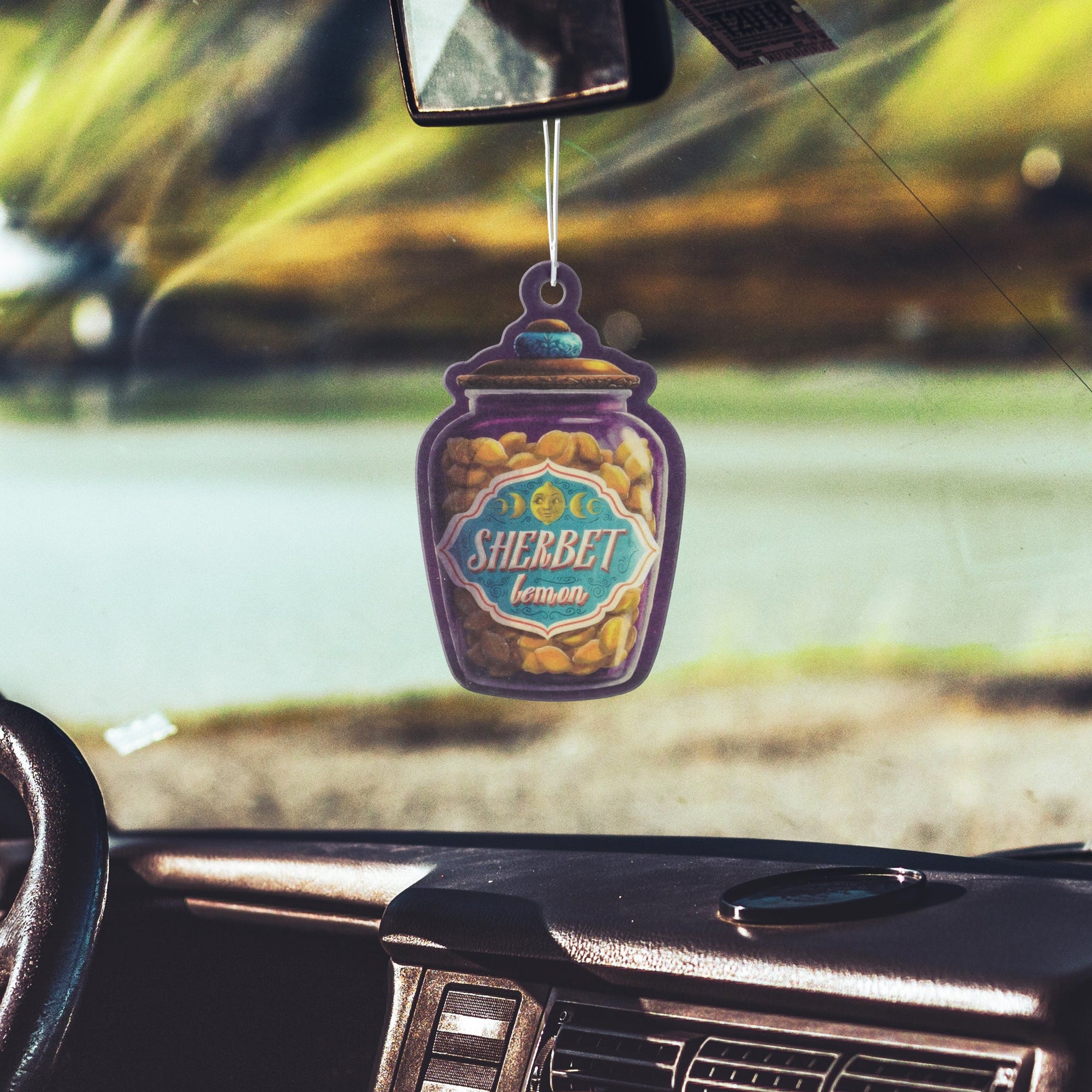 Sherbet Lemons Air Freshener is a flat purple jar containing lemon drops and hanging from a string