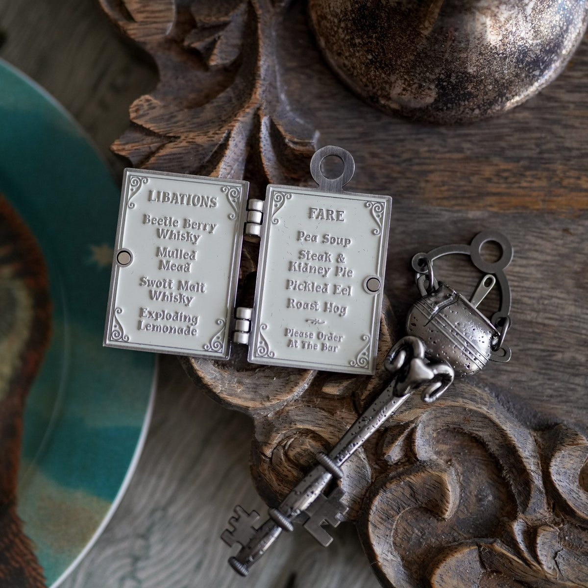The Cracked Kettle Pub Key with a cauldron head, hinged libation menu charm, and a hanging sign charm.