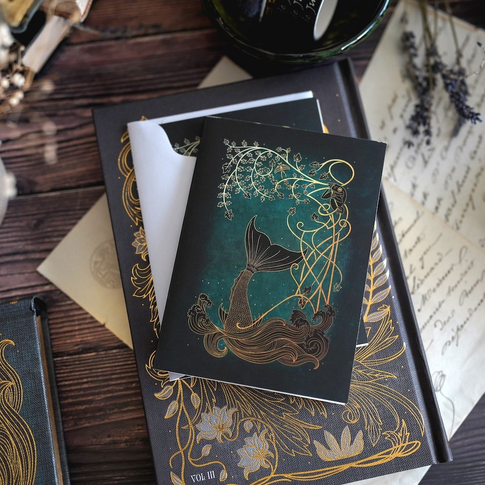 The Cruel Prince Stationary with magical images displaying a dagger, horses, snakes, mermaids, and characters from the book.