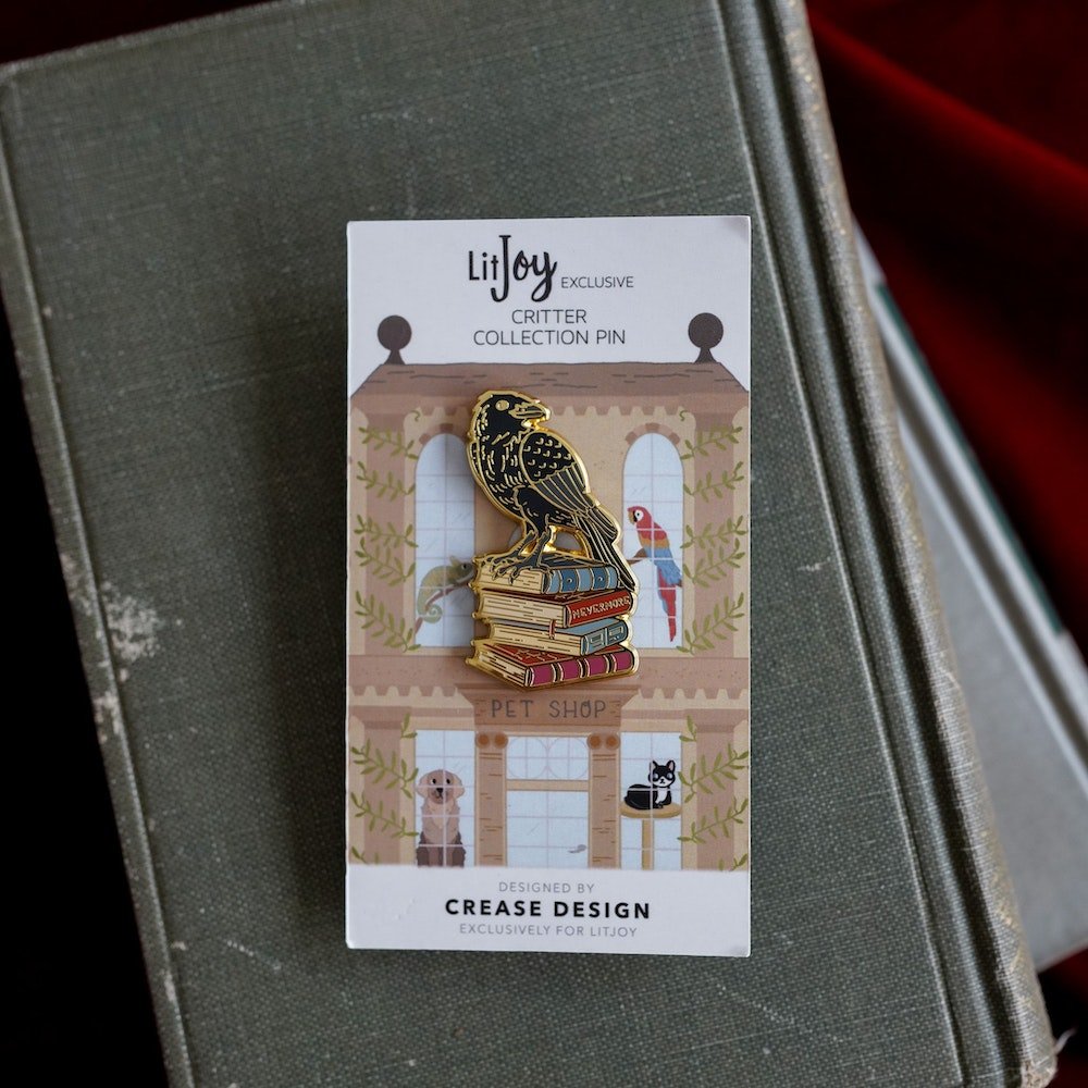 The Raven Critter Collection Enamel Pin with a raven standing on top of four books.