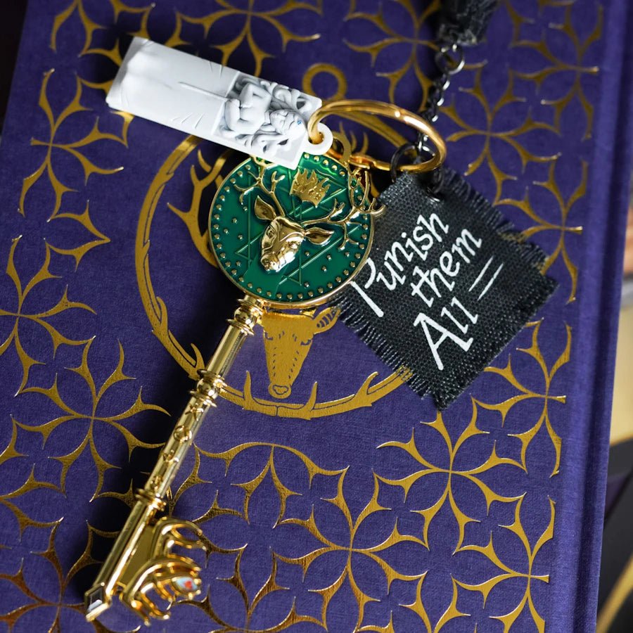 Sarah J. Maas Throne of Glass Key with a design of an amulet, a piece of cloth, a black rock, and Elena's sarcophagus.